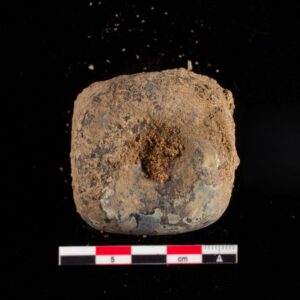 A small glass bottle, excavated at Jamestown, viewed from the top looking down into the bottle. The bottle is covered in dirt and the interior is obscured.